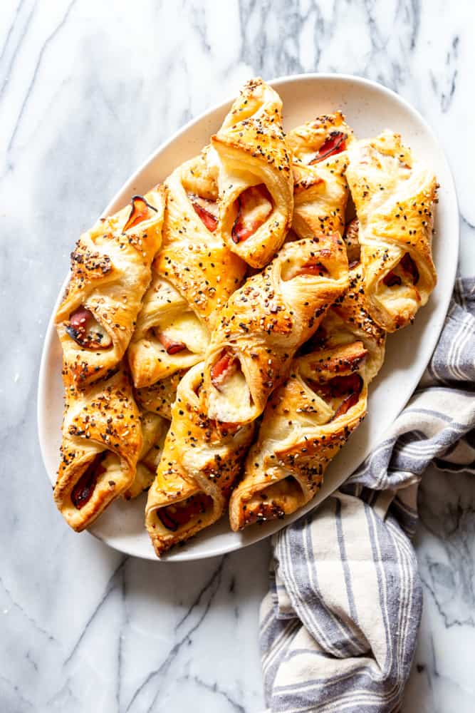 Ham and Cheese puff pastry appetizers on a white platter.