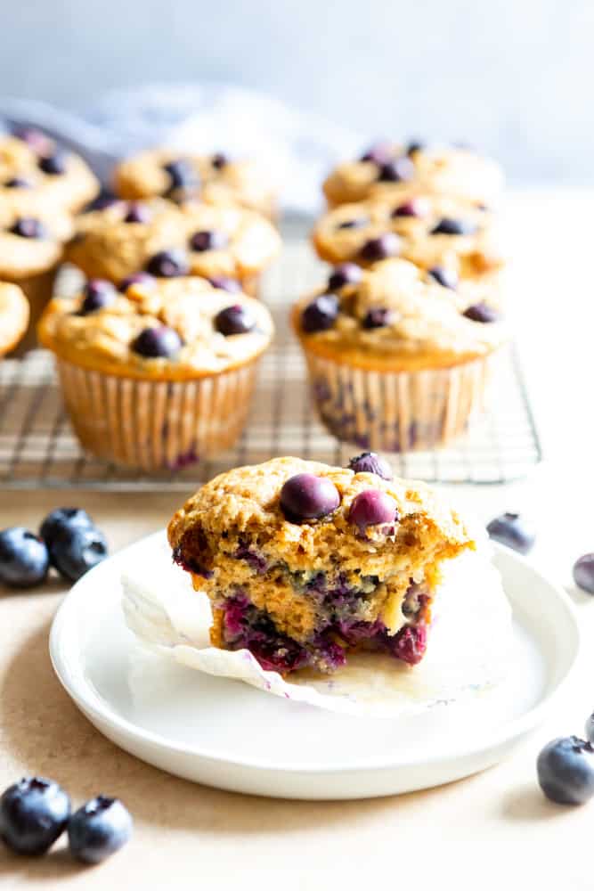 Healthy blueberry muffin half on a white plate.