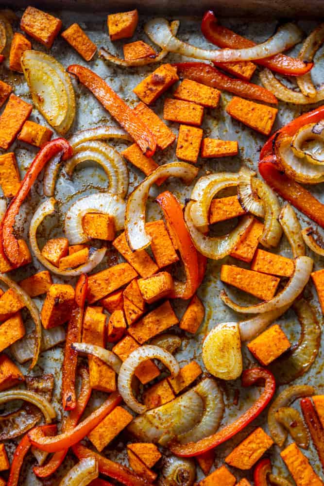 Roasted sweet potato, onion, and red bell pepper on a sheet pan.