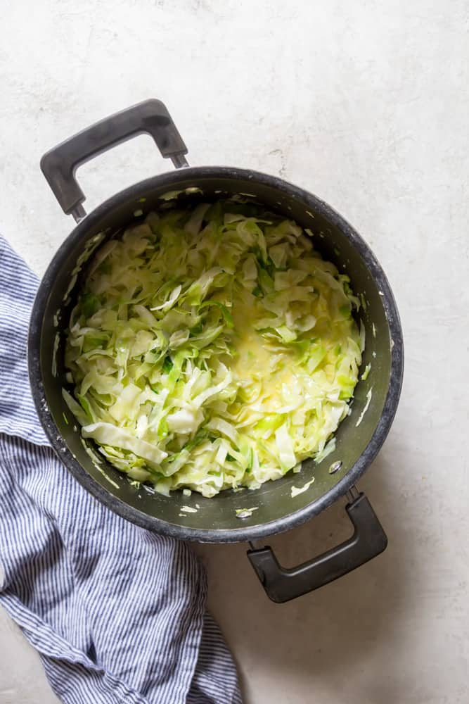 Sliced cabbage in a pot with butter and milk.