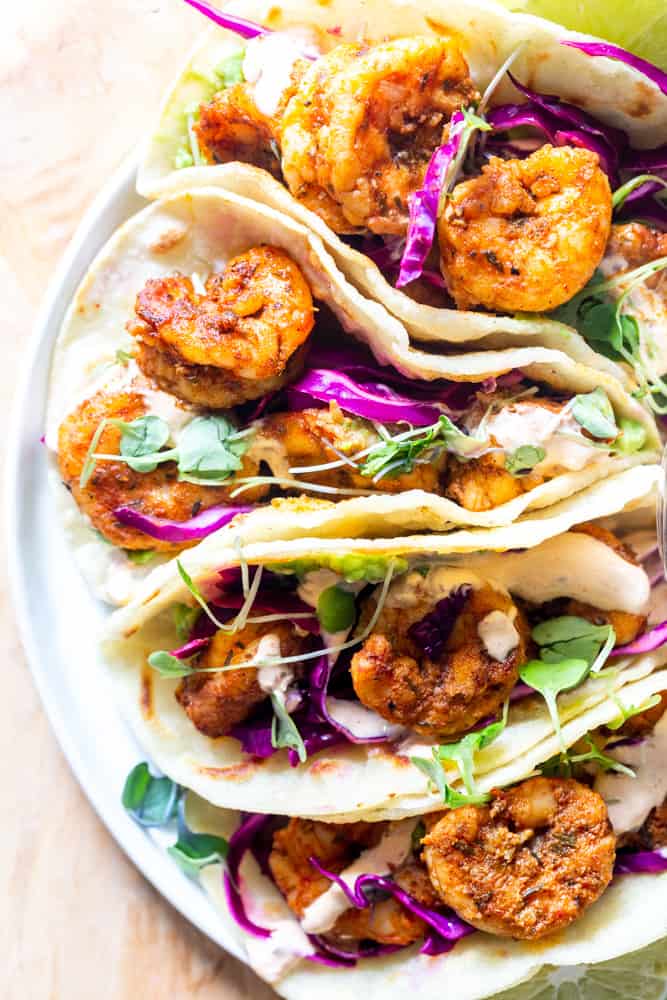 Close up of blackened shrimp tacos with cabbage slaw and microgreens