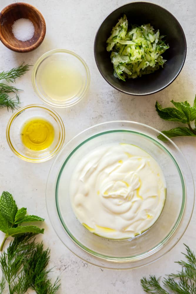 Ingredients for tzatziki sauce - Greek yogurt, grated cucumber, lemon juice, olive oil, salt.