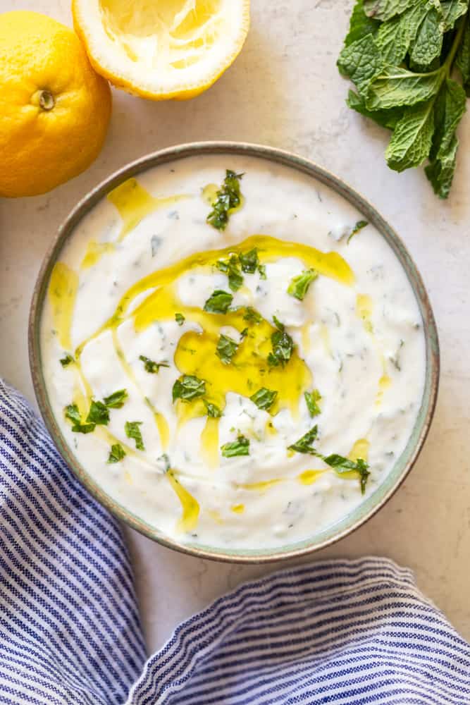 Greek Tzatziki Sauce in a bowl, garnished with mint and olive oil.