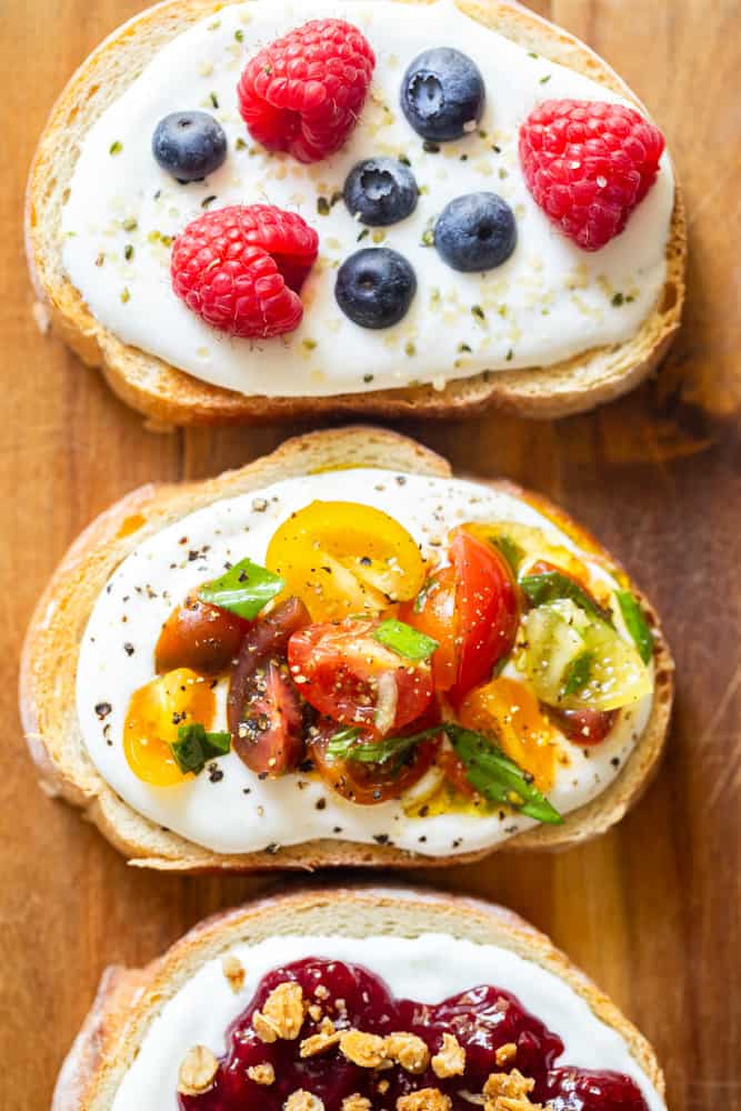 Toast with whipped cottage cheese spread and marinated tomato bruschetta topping on a wooden board