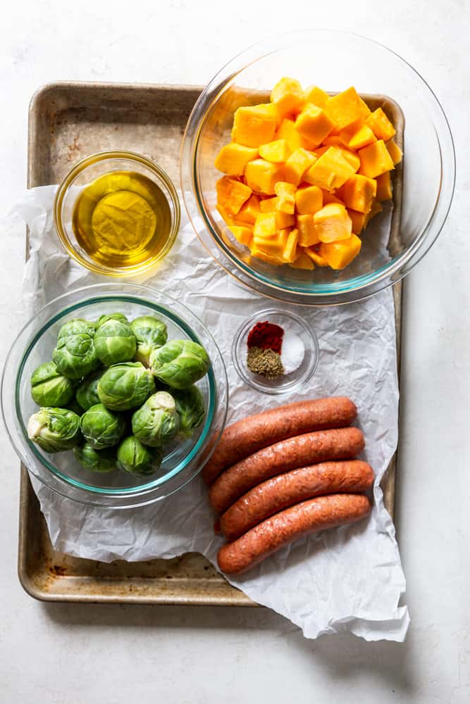 Ingredients for Sausage butternut squash sheet pan dinner - cubed butternut squash, brussels sprouts, olive oil, sausage links, spices.