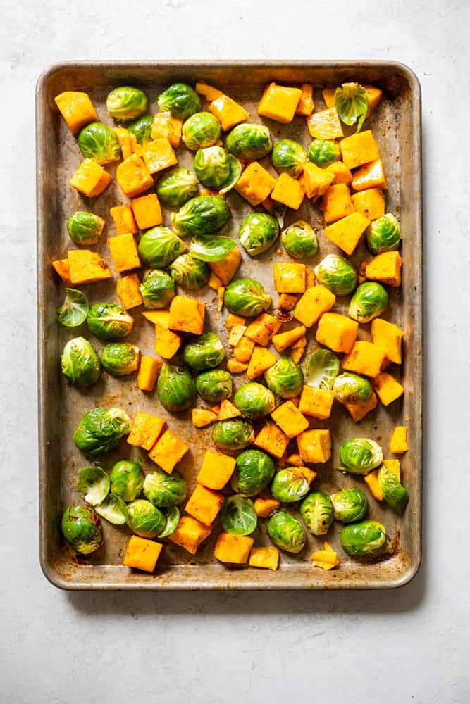 Brussels sprouts and butternut squash on a sheet pan before cooking.