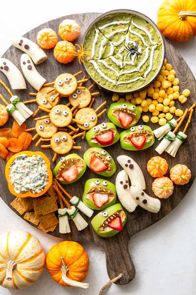 Healthy Halloween Snack Board with Spider Web Guacamole, Boo-Nanas, Clementine Pumpkins, Witches Brooms, Apple Monsters and Spider crackers