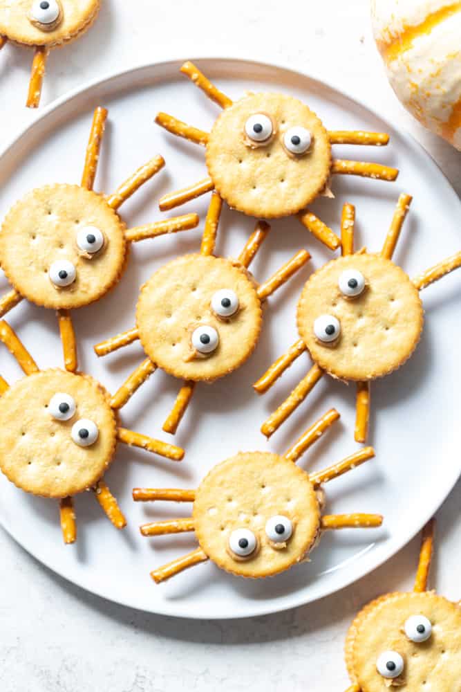 Cracker "spiders" Round butter crackers sandwiched with nut butter, Pretzel sticks make the spider legs and candy eyes are attached to the top to make the crackers look like cute spiders.