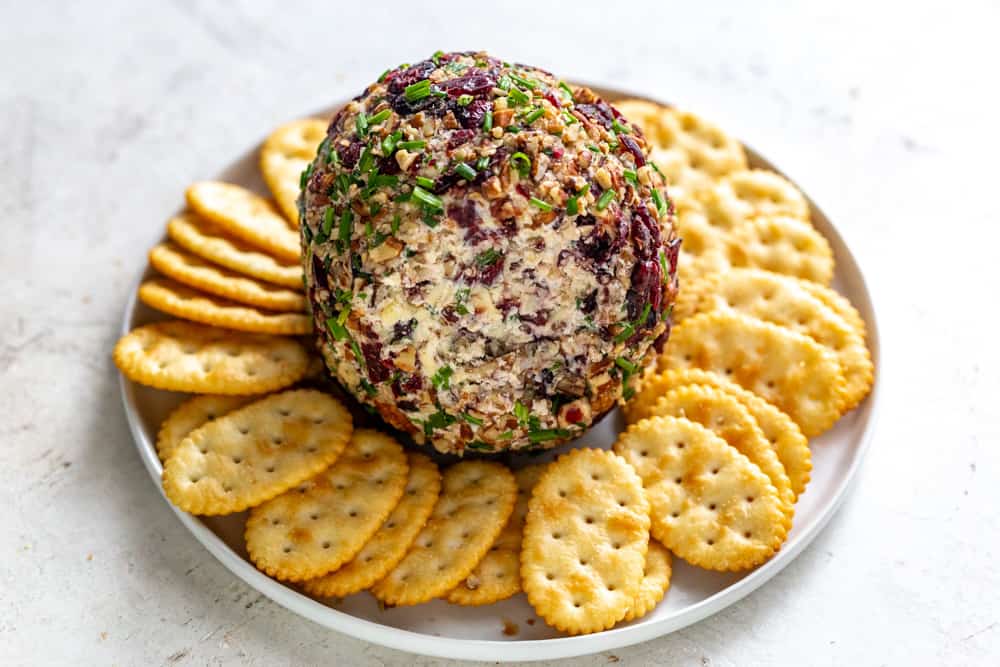 Cranberry Pecan Cheese Ball on a plate with crackers.