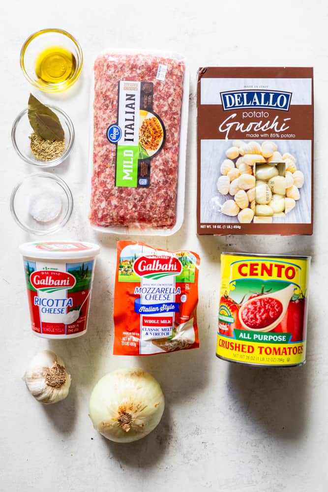 ingredients for one pot gnocchi - ground sausage, shelf stable gnocchi, ricotta cheese, whole milk low moisture mozzarella, crushed tomatoes, garlic, onion, salt, dried oregano, dried bay leaf, olive oil.