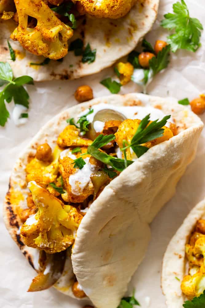 Spiced cauliflower and chickpeas in a pita, drizzled with garlic yogurt sauce and garnished with fresh parsley.