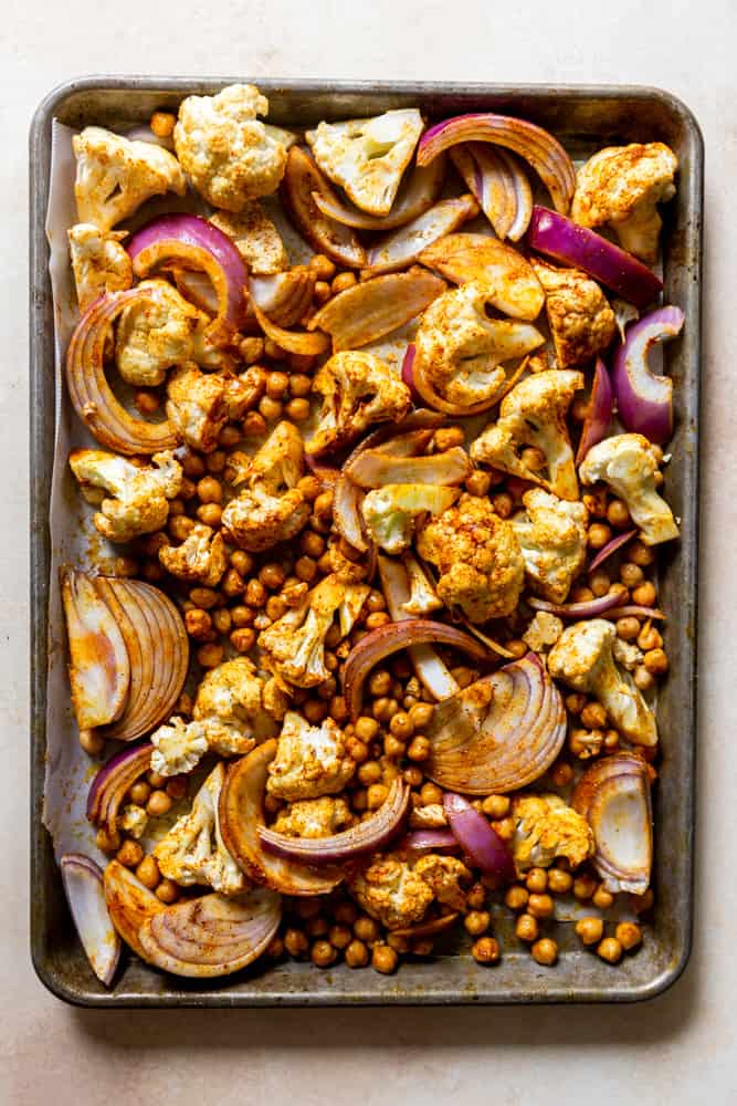 Sheet pan with spiced cauliflower, chickpeas and onion before roasting.