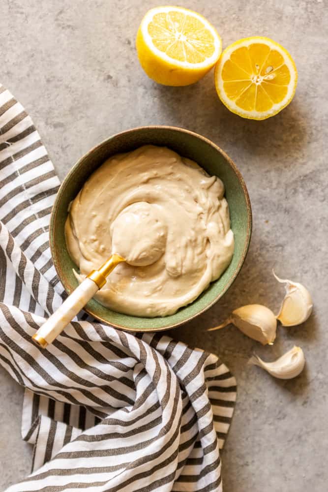 Tahini sauce in a small green bowl with a spoon.