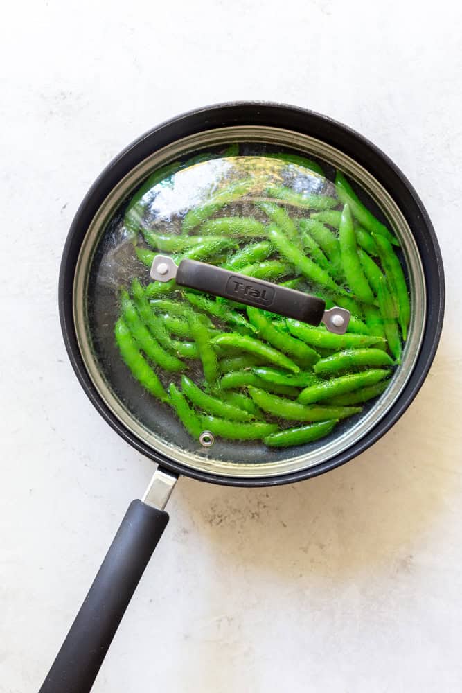 Snap peas in a saute pan covered with a glass lid
