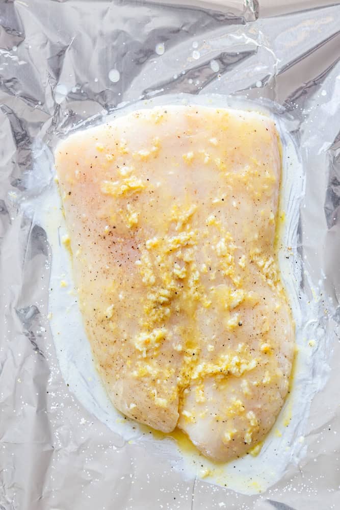 Halibut Filet before being baked, brushed with garlic butter on a foil lined baking sheet. 