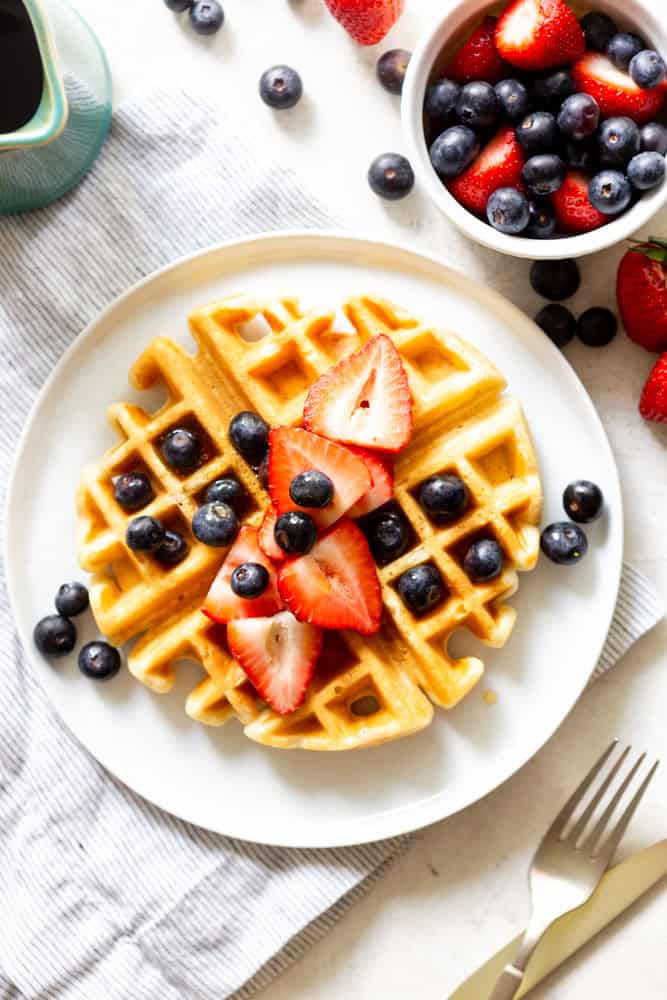 Buttermilk waffle topped with fresh fruit and maple syrup.