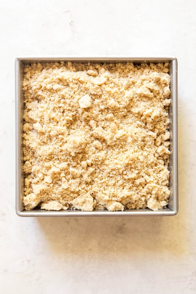 Square metal backing pan with rhubarb crumble before baking.