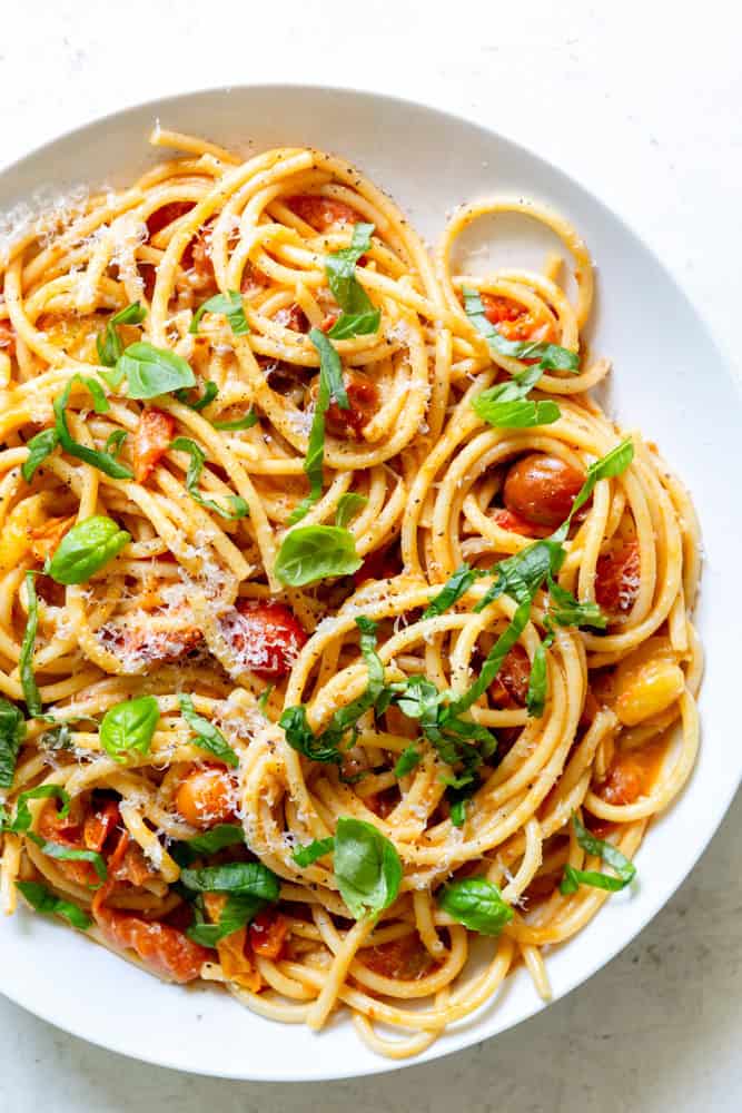 Burst Cherry Tomato Pasta garnished with basil and fresh grated parmesan cheese.
