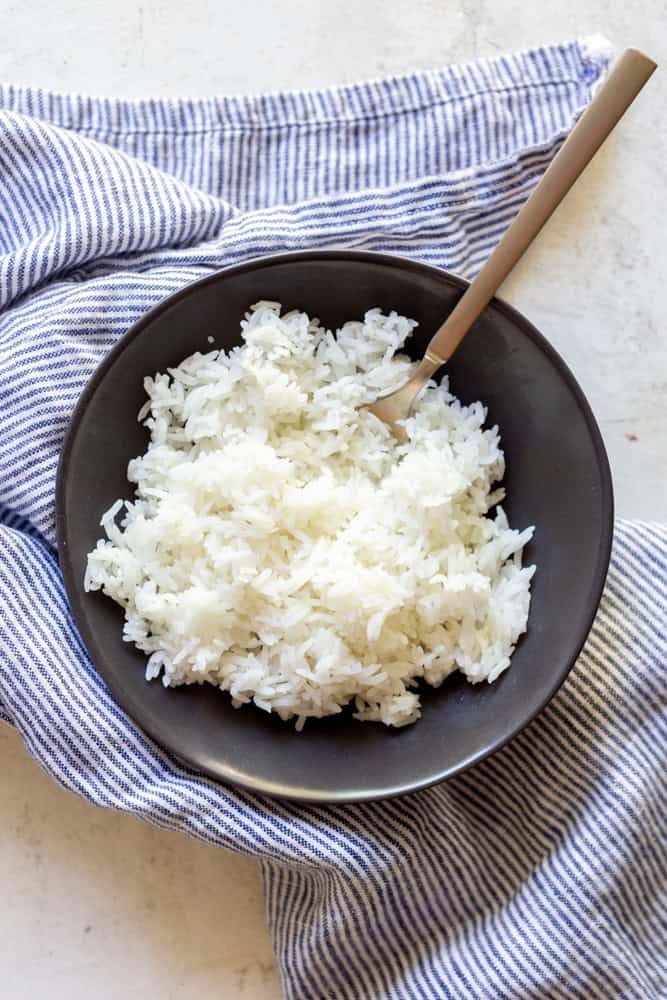 Long grain white rice in a black bowl.