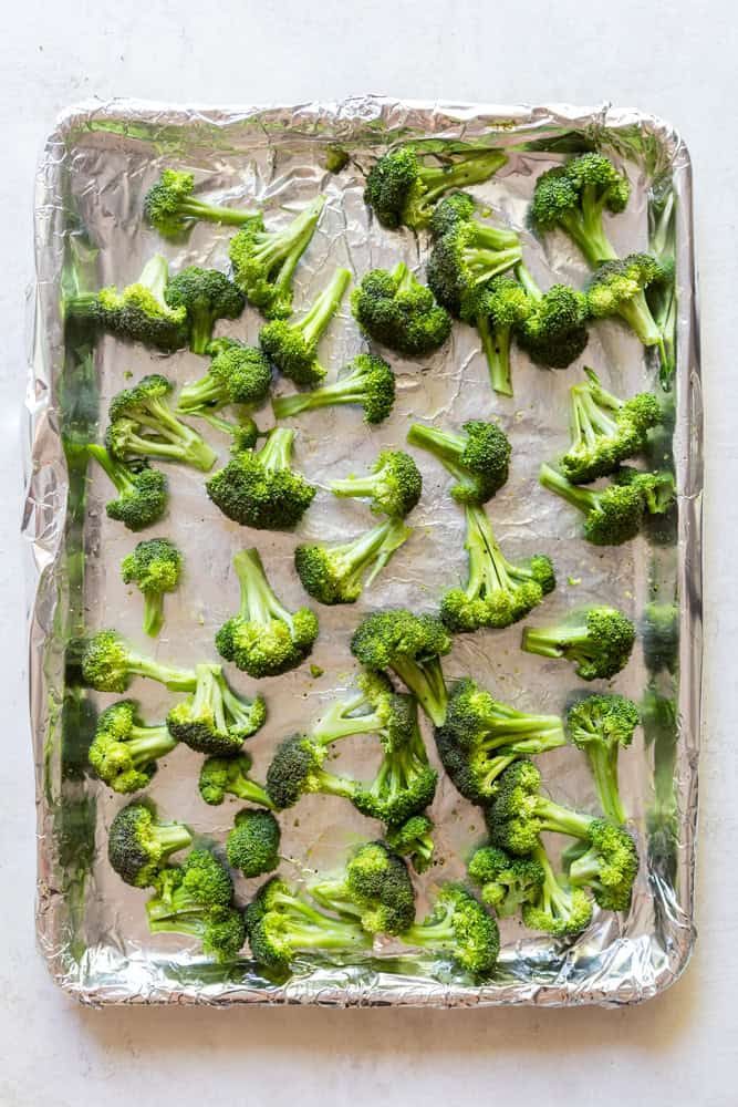 Broccoli florets on a foil lined sheet pan.