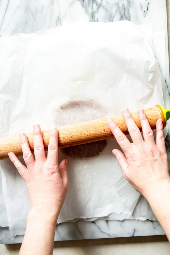 Rolling the gingerbread dough between two sheets of parchment paper.