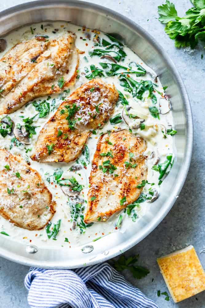 Golden brown chicken breasts in a creamy mushroom spinach sauce.