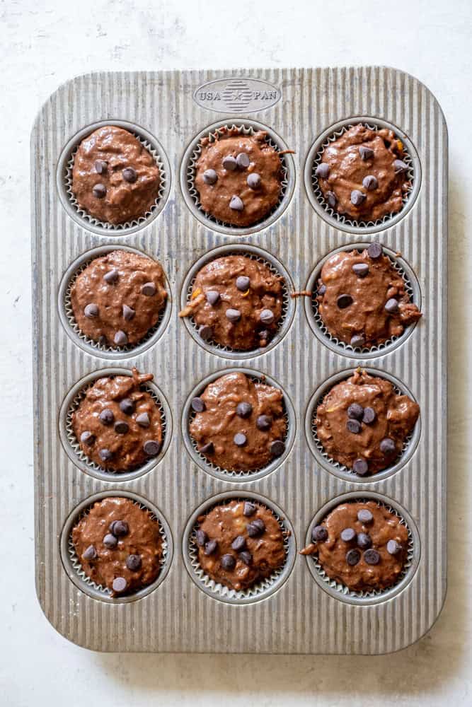 12 cup muffin tin filled with chocolate zucchini muffin batter.  Fill each cavity to the top. 