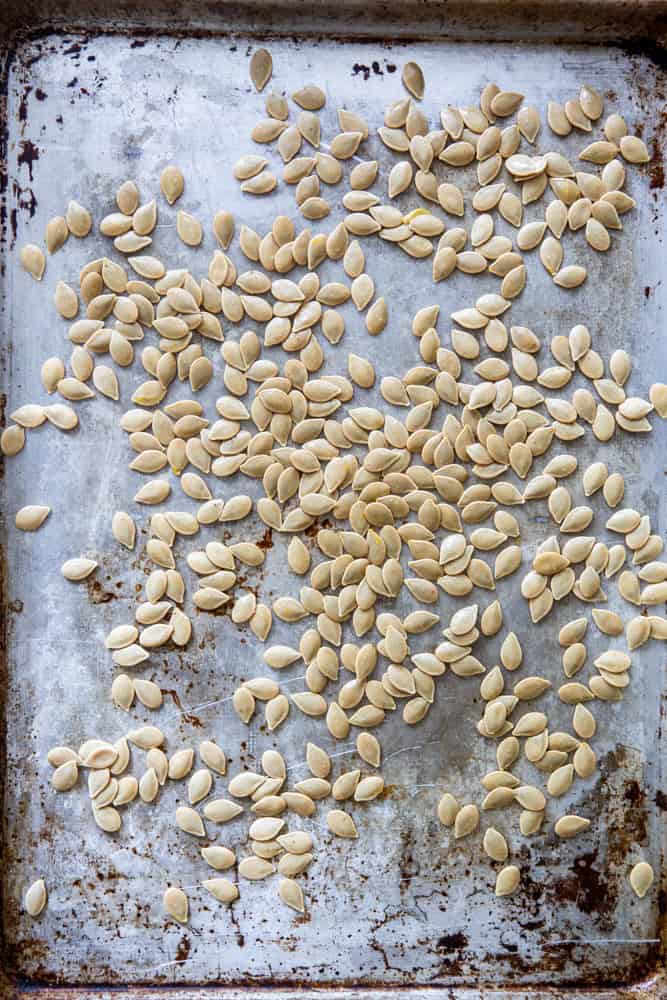 Pumpkin seeds on a baking sheet before being roasted.