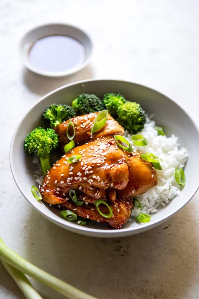 Soy Ginger Chicken thighs with rice and broccoli in a white bowl.