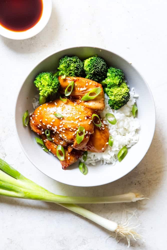 Soy Ginger Chicken Thighs with broccoli and rice in a white bowl.