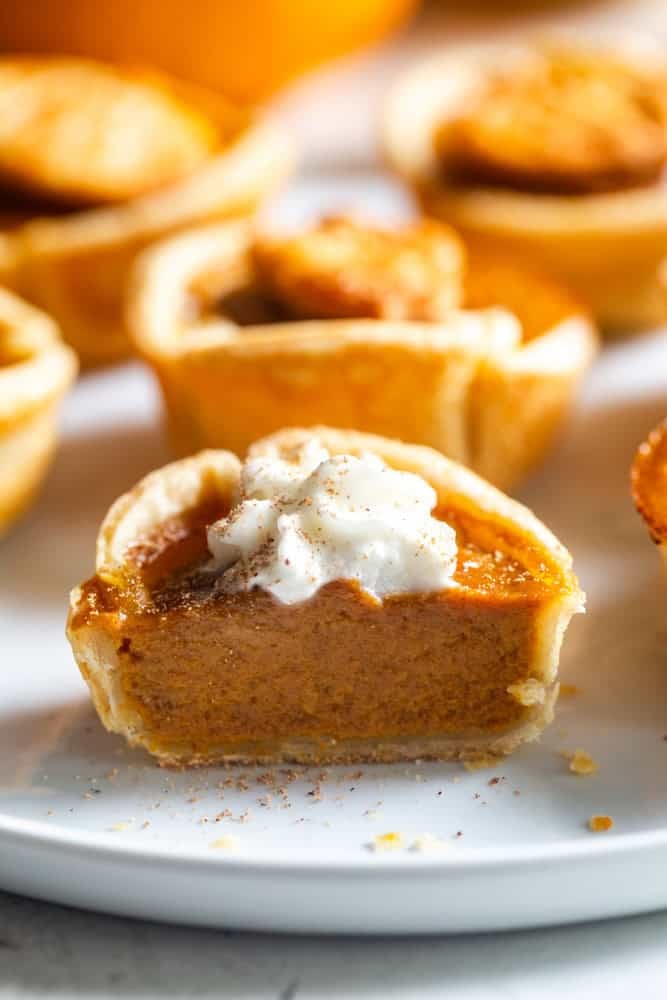 A mini pumpkin pie cut in half on a white plate.