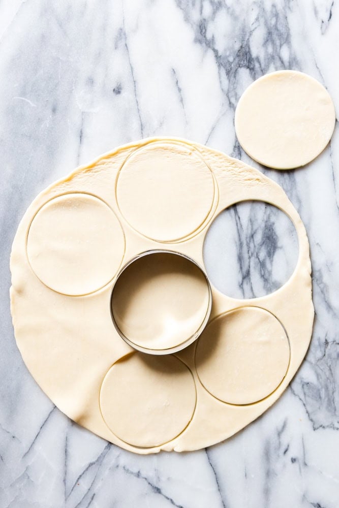 Pie crust being cut into small circles for mini pies.