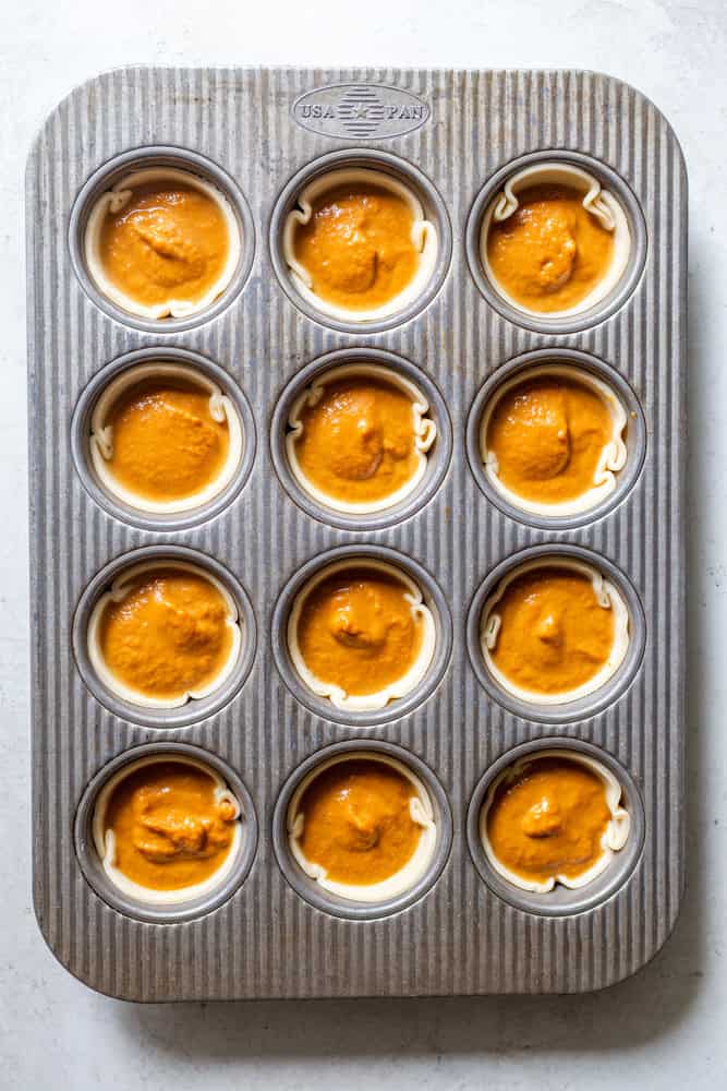 Mini Pumpkin pies in a 12 cup muffin tin before baking.